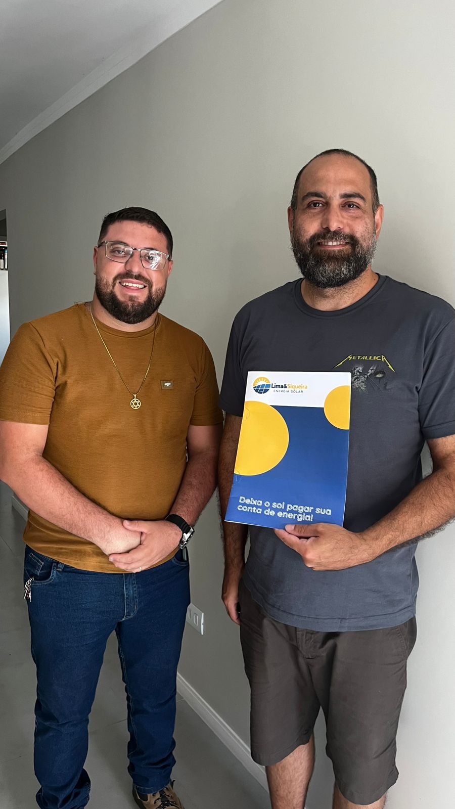 Douglas junto ao cliente segurando uma proposta de energia solar